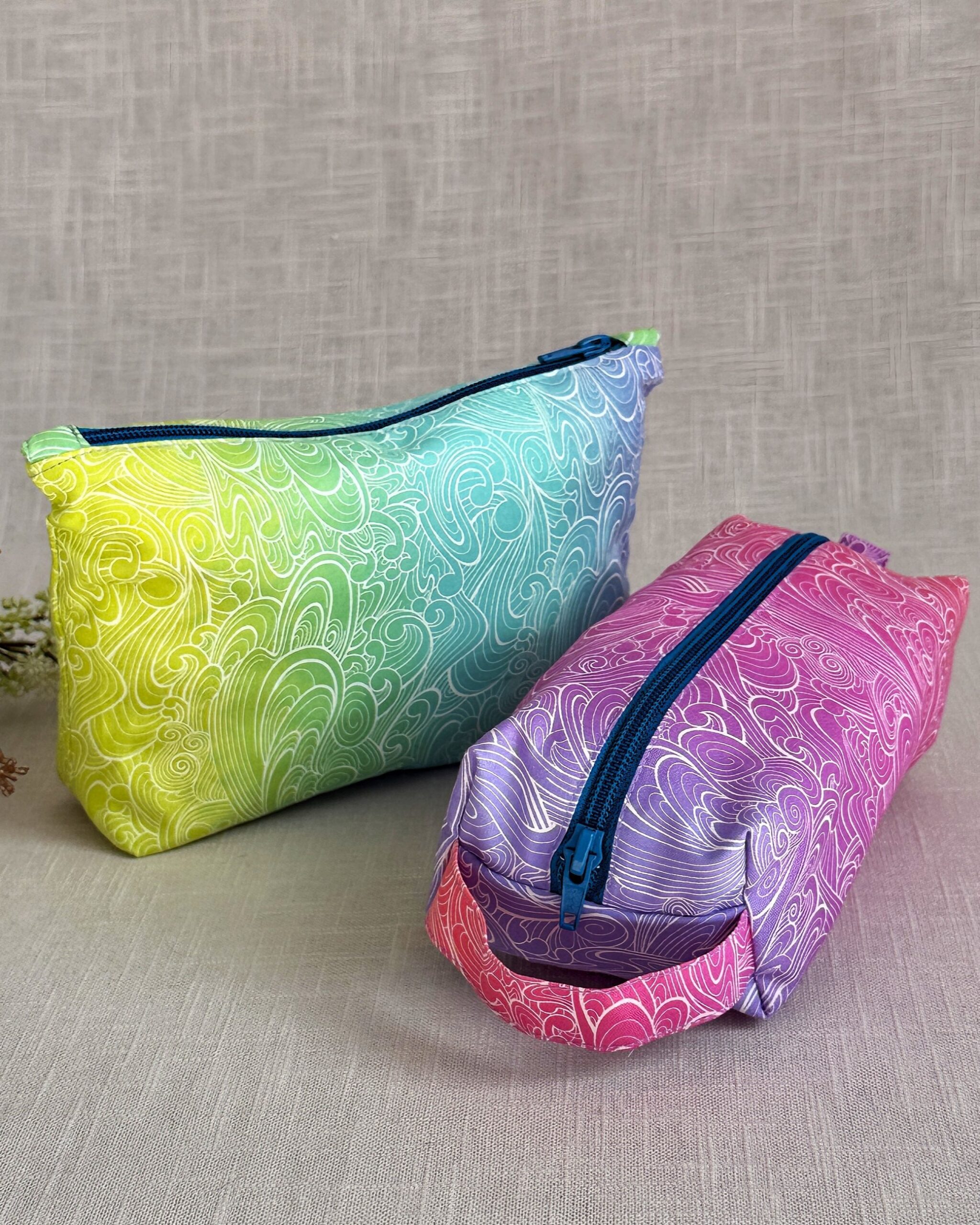 Two handmade zipper bags, including a makeup bag and a boxy pencil case, made with a PDF sewing pattern.